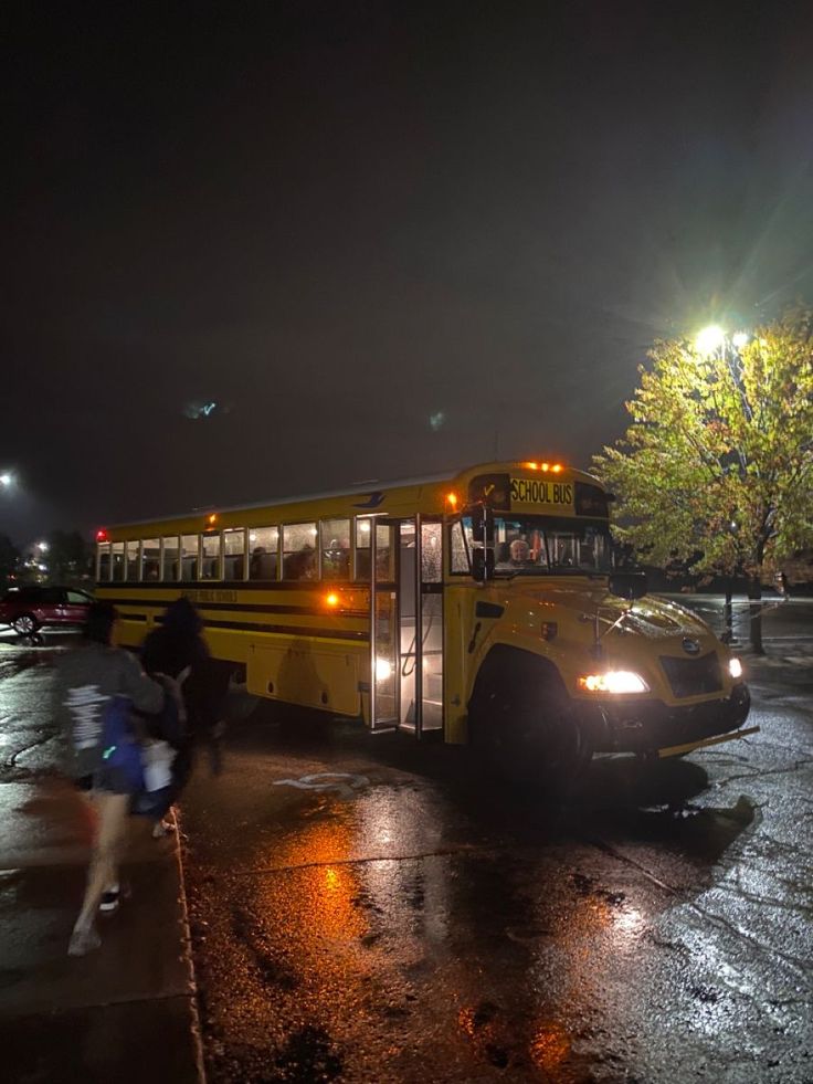 a school bus parked on the side of the road at night with its lights on