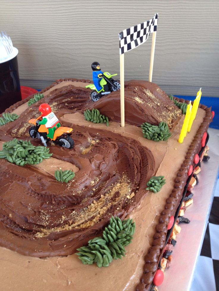 a birthday cake that is shaped like a dirt bike race track with cars on it