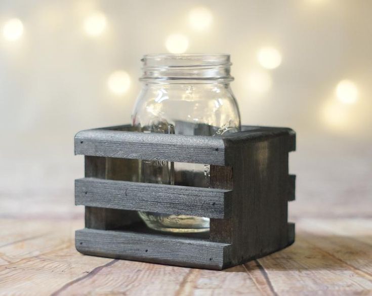 a mason jar sitting on top of a wooden box next to a glass filled with coins