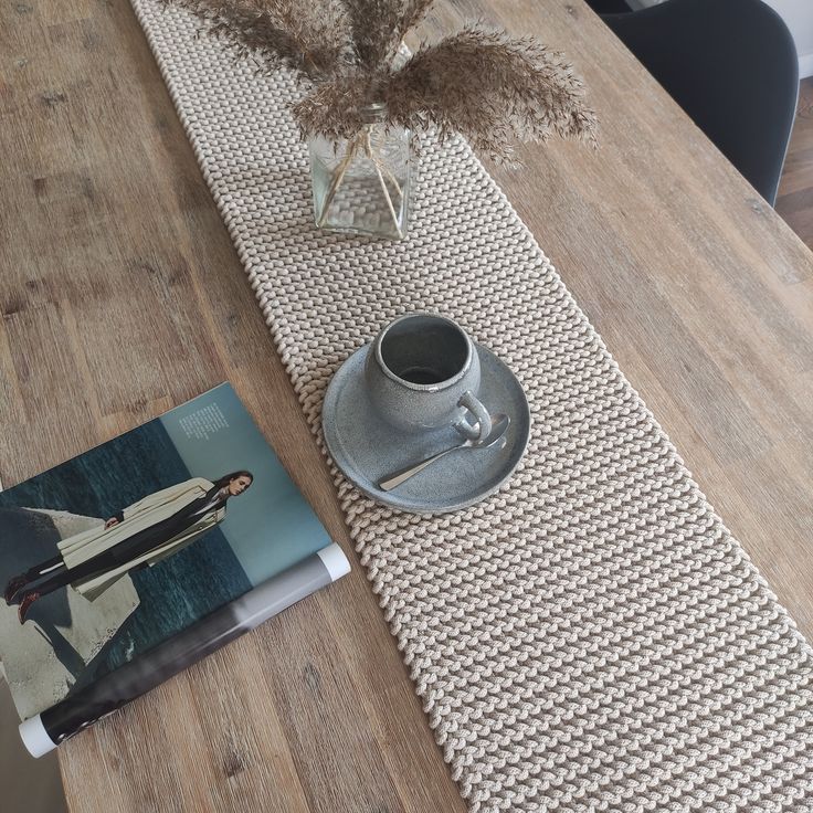 a table with a book, coffee cup and vase on it