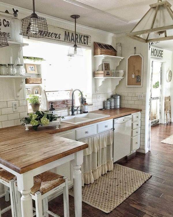 a kitchen with white cabinets and wooden counter tops in front of an open floor plan