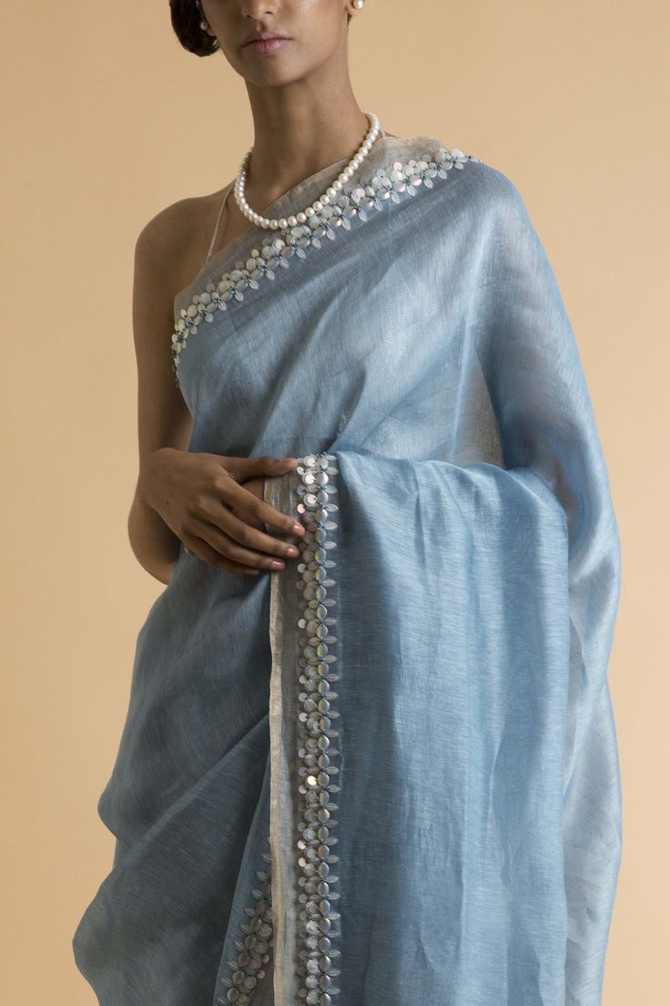 Editor's NoteThis set features a powder blue saree handwoven with linen and silk yarns. This piece is glorified by pearl white shells along the delicate light golden border. This saree comes with a matching blouse piece. Fabric: Linen Silk Sleeve Type: Strap Dimension: Length: 5.5m; Width: 1.1m Components: Saree and unstitched blouse piece Care: Dry Clean Only Customize Your OutfitCan't find the size you're looking for? No stress. Just select size "Custom" while adding the item to your cart. We Light Blue Saree For Farewell, Light Blue Silk Saree Blouse Designs, Traditional Summer Pre-draped Saree With Zari Work, Linen Chikankari Embroidery Wedding Sets, Elegant Cotton Silk Blouse Piece With Embroidered Border, Wedding Linen Sets With Chikankari Embroidery, Designer Summer Dupatta With Embroidered Border, Wedding Linen Set With Resham Embroidery, Traditional Linen Sets For Diwali