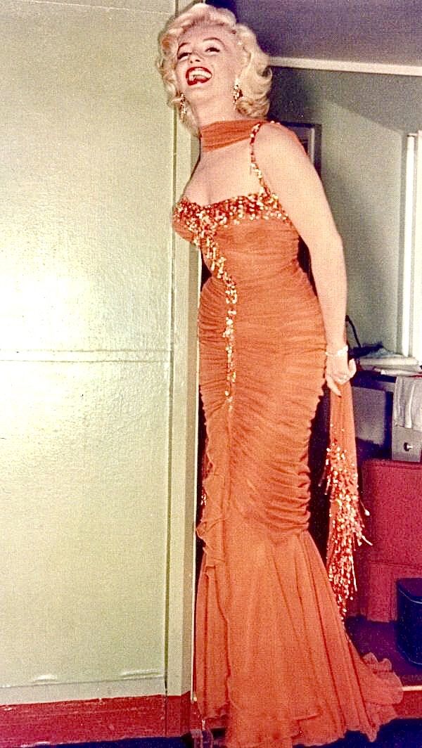 a woman in an orange dress is posing for the camera