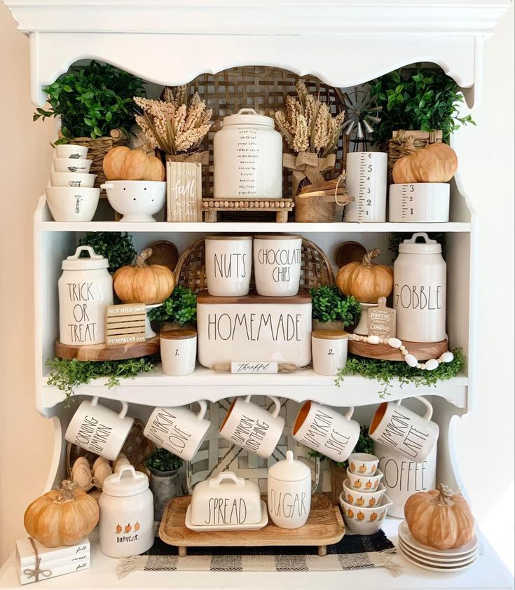 a white hutch filled with lots of dishes and pumpkins on top of it