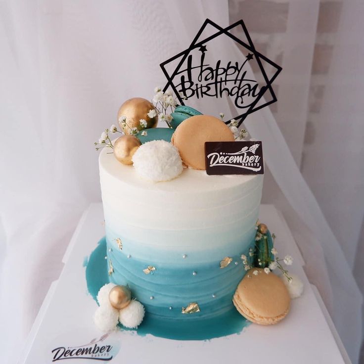 a birthday cake with frosting and decorations on the top is decorated in blue, white and gold