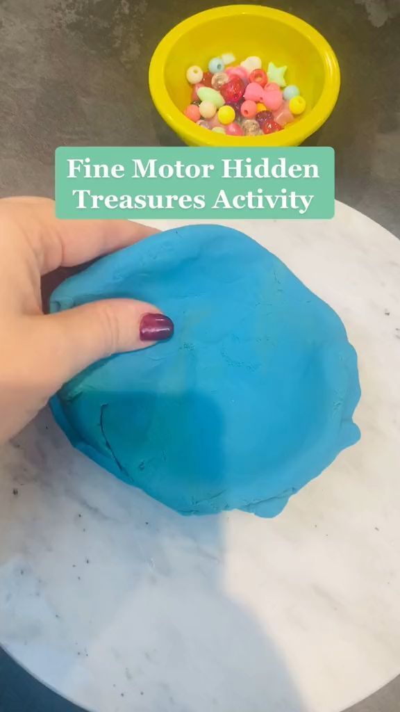 a hand holding a blue plastic object over a white table with a yellow bowl on it