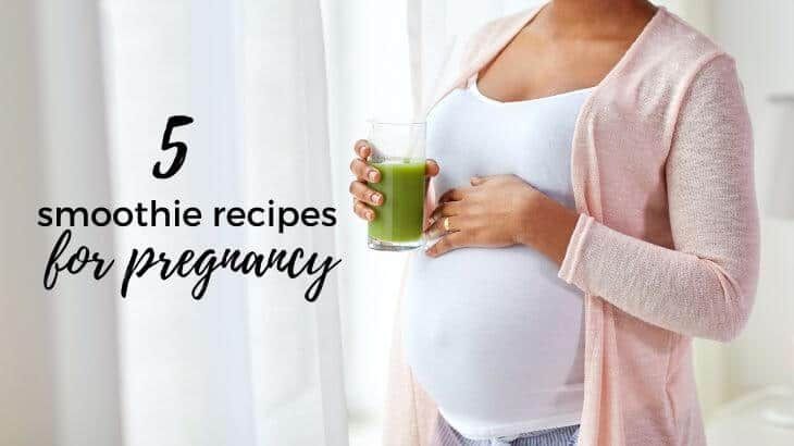 a pregnant woman holding a glass of green smoothie