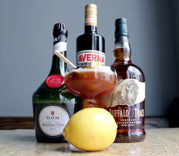 an apple, lemon and two bottles of alcohol sit on a counter next to each other