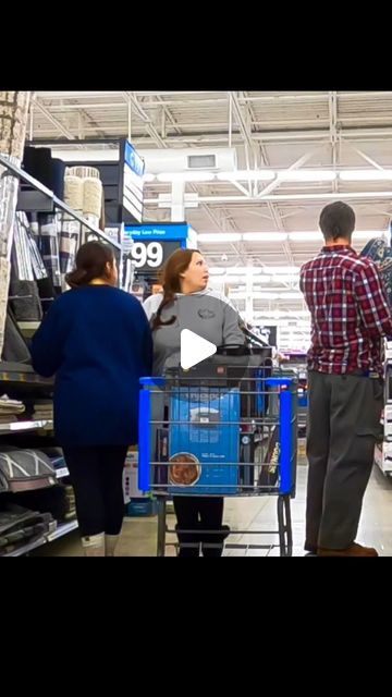 people are shopping in a store with the man pushing a cart behind them and talking to another person