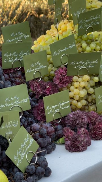 there are many grapes and other fruits on the table with name tags attached to them