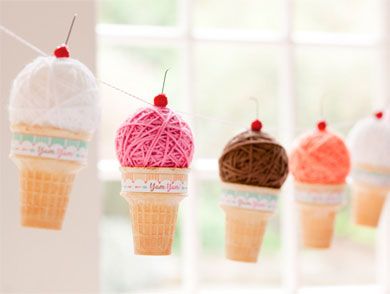 ice cream cones are hanging from strings in front of a window with yarn on them