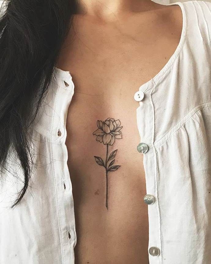 a woman's chest with a flower tattoo on her left side ribcage