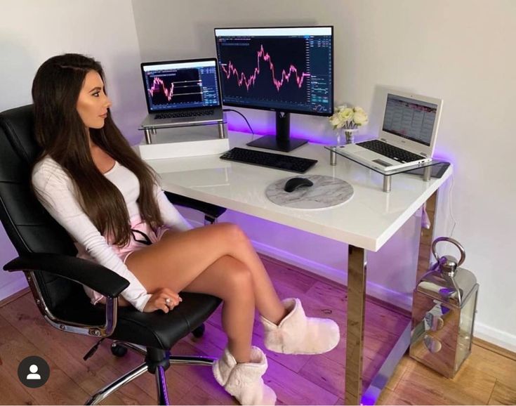 a woman sitting at a desk in front of two computer monitors