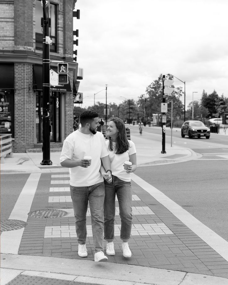 a man and woman standing on the side of a road next to a cross walk