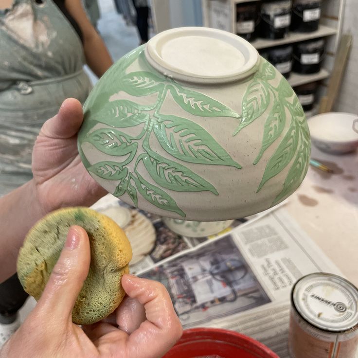 a person holding a green vase over a red bowl with food in it on a table