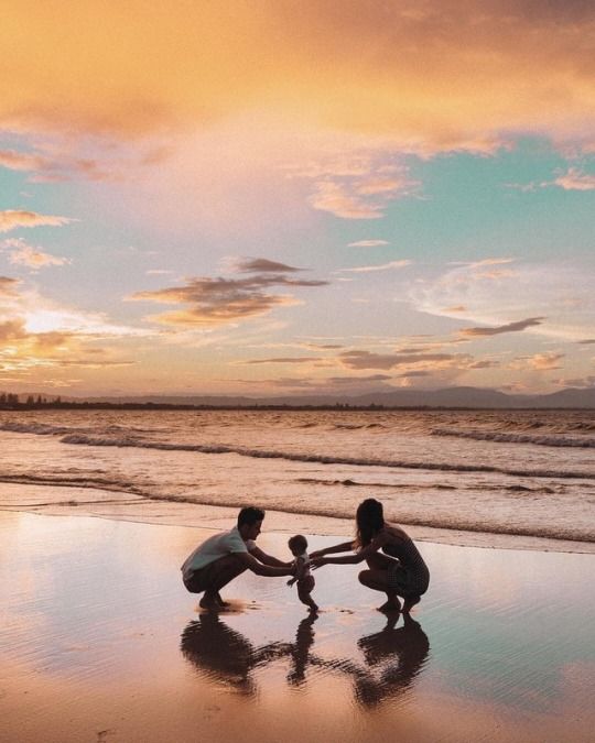 two people holding hands on the beach at sunset