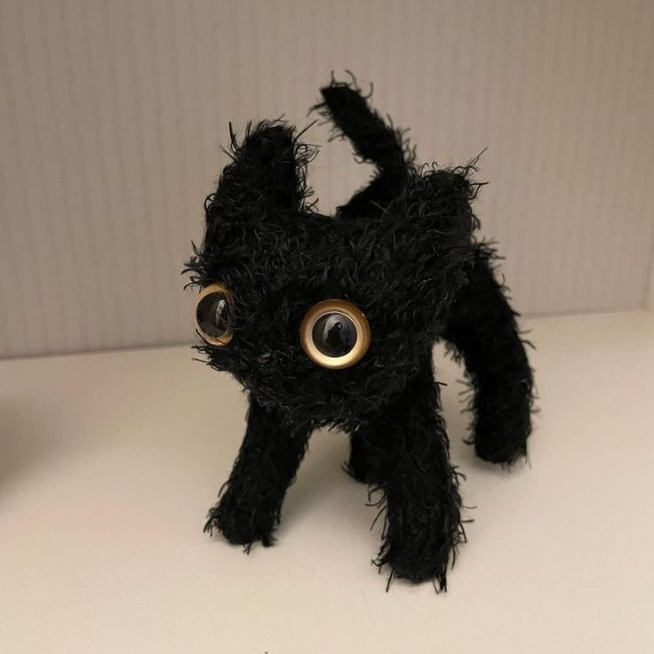 a black stuffed animal with big eyes on a table