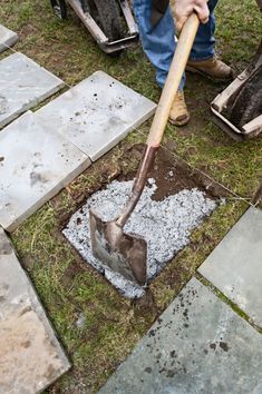 a man is digging in the ground with a large shovel and some cement blocks behind him