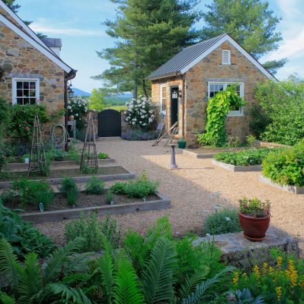 an outdoor garden area with various plants and flowers in the foreground, surrounded by stone buildings