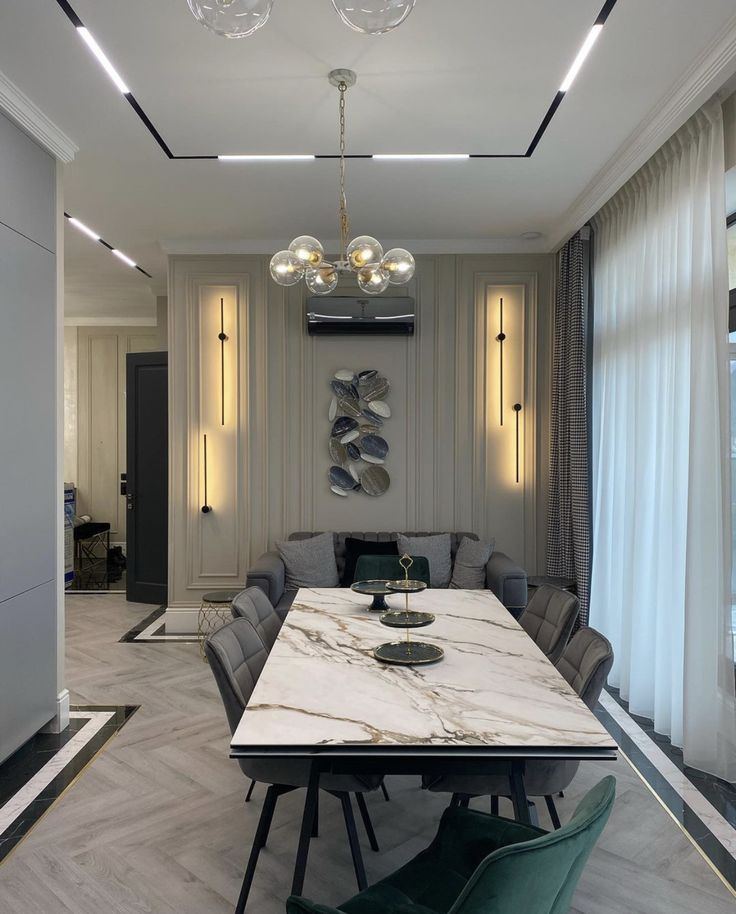 an elegant dining room with marble table and green chairs in front of the wall mounted chandelier