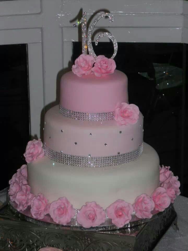 a three tiered cake with pink flowers on the bottom and bling in the middle