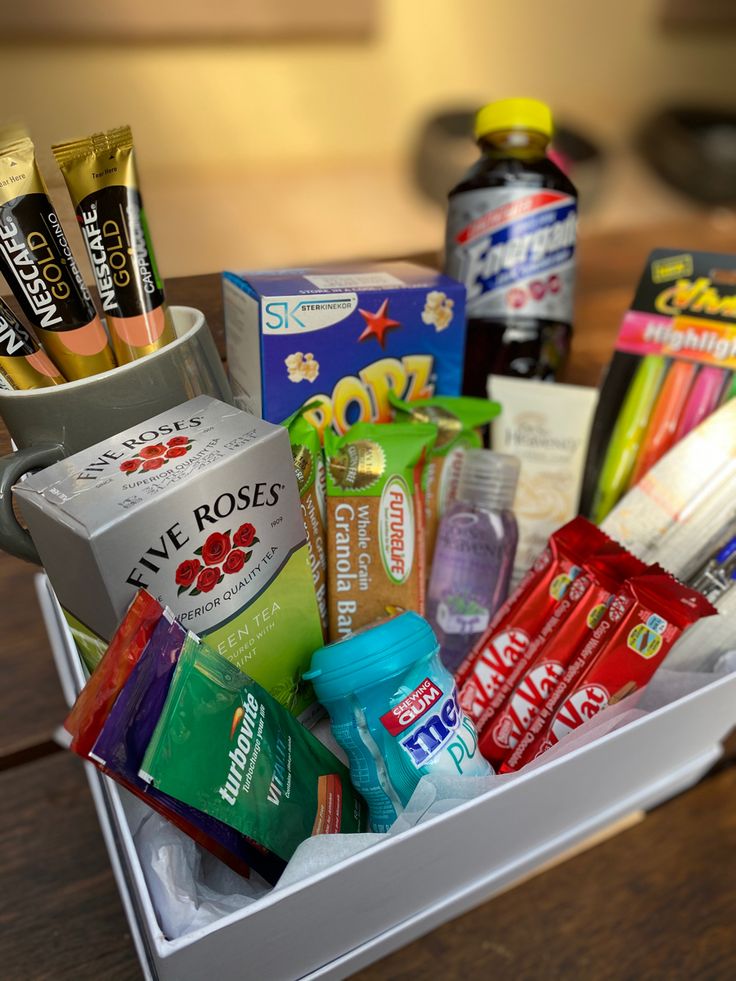 a white box filled with lots of different types of snacks and drinks on top of a wooden table