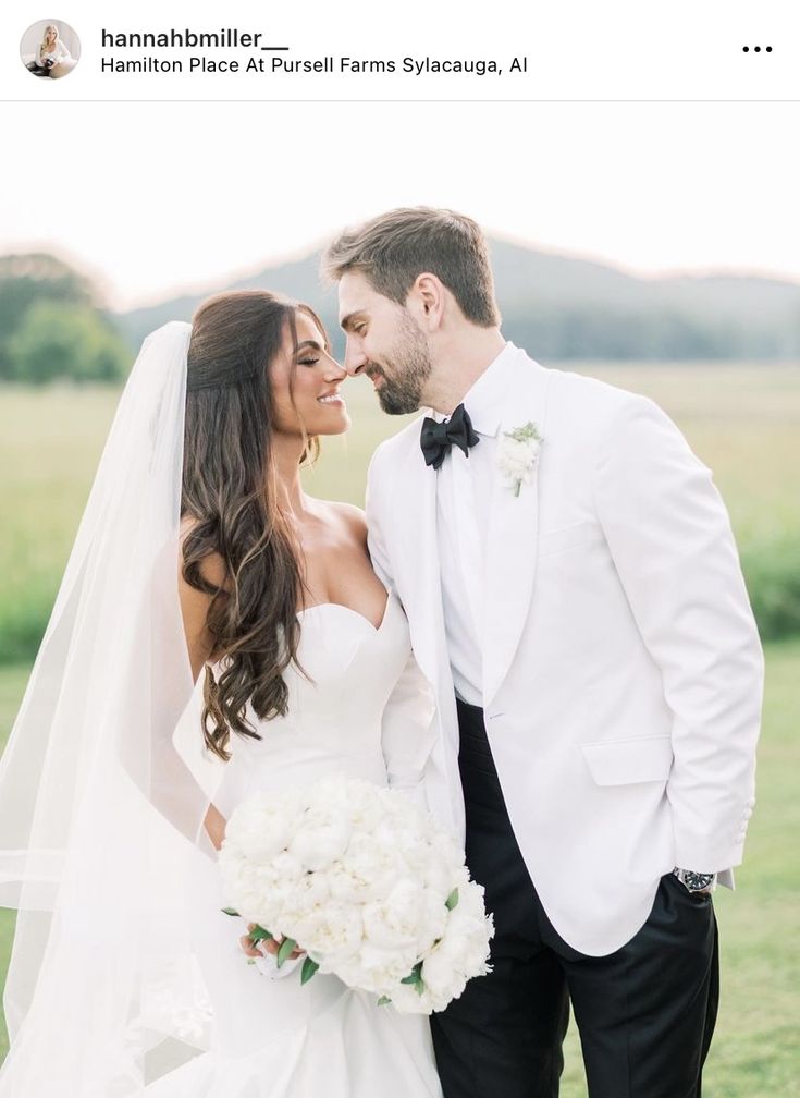 a bride and groom posing for a photo in front of a green field with white flowers