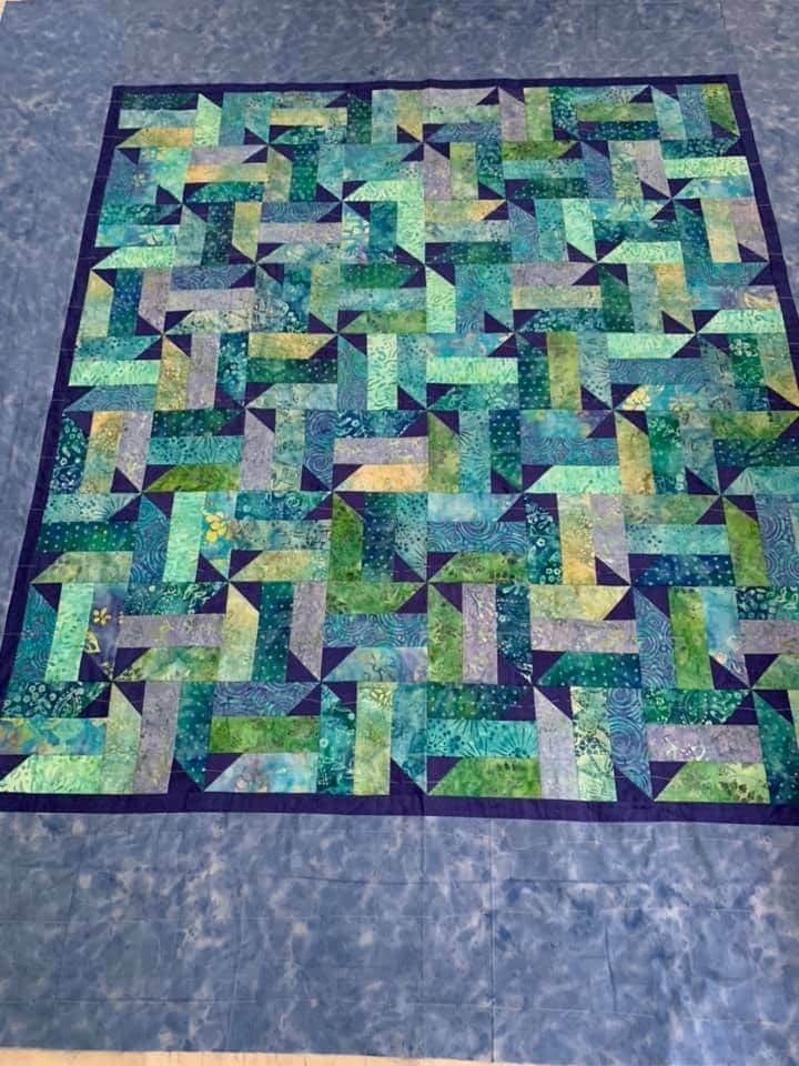 a blue and green quilt is laying on the floor