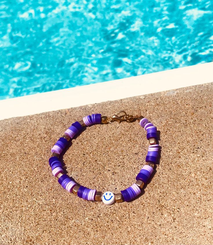 Cute purple ombré bracelet with gold charms and a smiley face Purple Heishi Bracelet, Purple Bracelet Ideas Clay Beads, Purple Bracelet Ideas, Purple Clay Bead Bracelet, Bracelets Preppy, Ombre Bracelet, Beaded Watches, Preppy Bracelets, Bracelet Diy