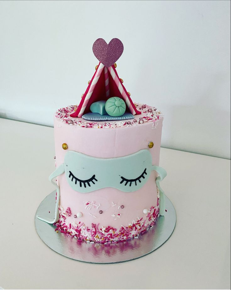 a pink cake with eyelashes and a tent on top