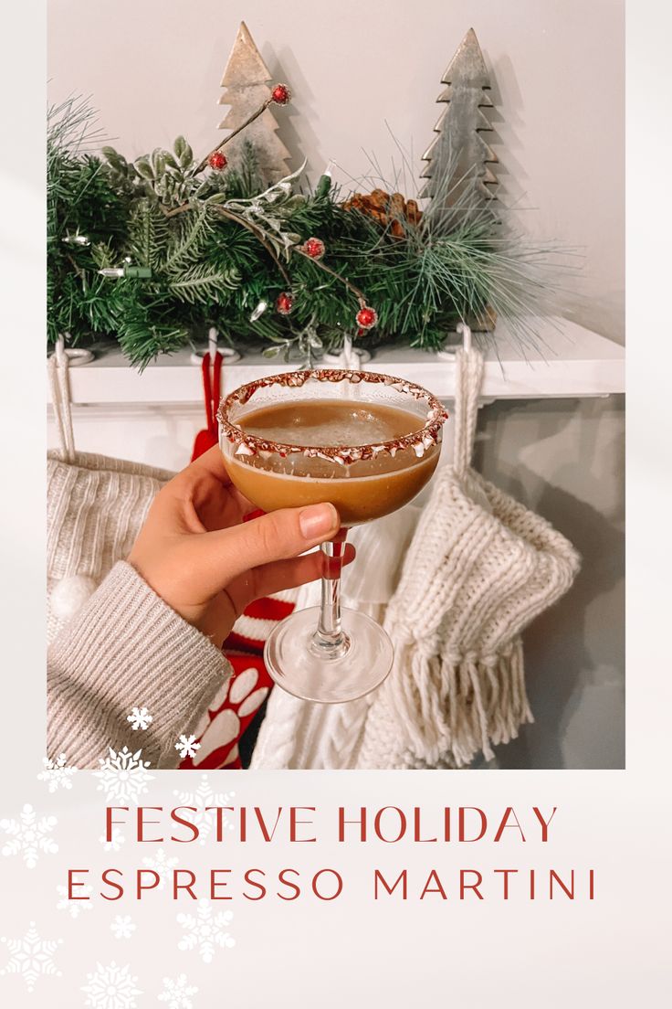 a person holding a martini glass in front of a fireplace with christmas decorations on it