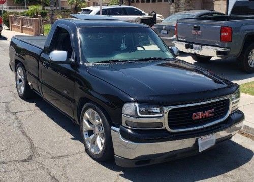 a black truck is parked on the side of the road in front of other cars