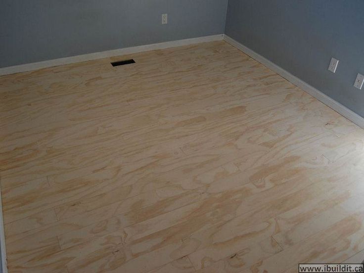 an empty room with hard wood flooring in the middle and blue walls behind it