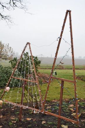 a wooden structure with lights on it in the middle of a field next to a tree