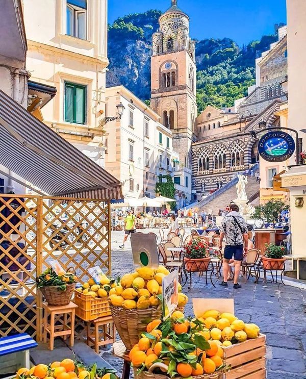 there are many oranges in baskets on the street outside this market place with people walking by