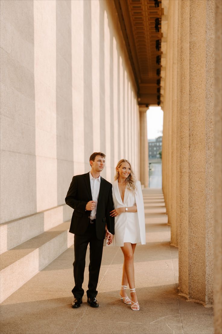 a man and woman in formal wear walking down the street together, both dressed in black and white