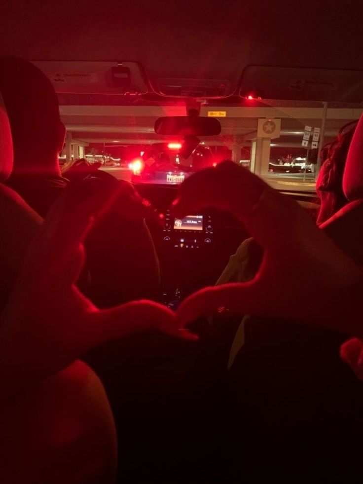 two people sitting in the back seat of a car with their hands on the steering wheel