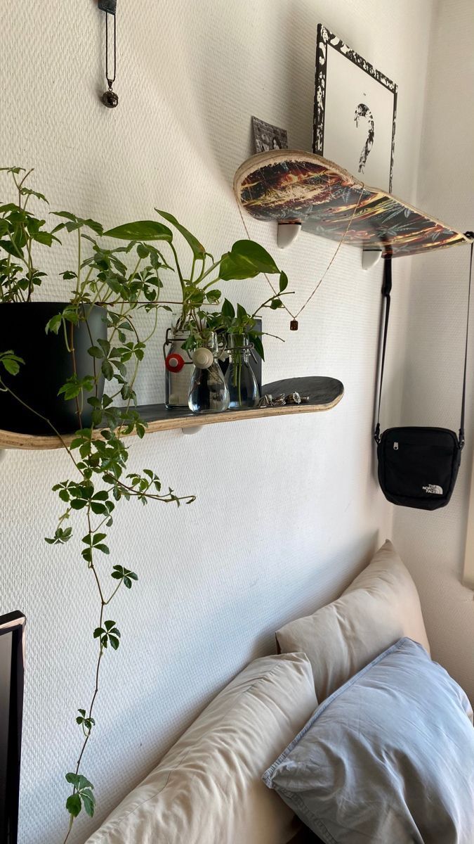 there is a shelf with plants on it in the corner next to a bed and pillows