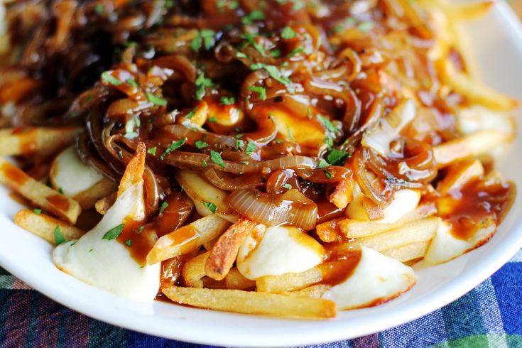 a white plate topped with french fries covered in sauce