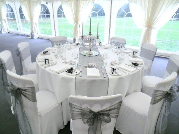 a banquet table set up with white linens and bows