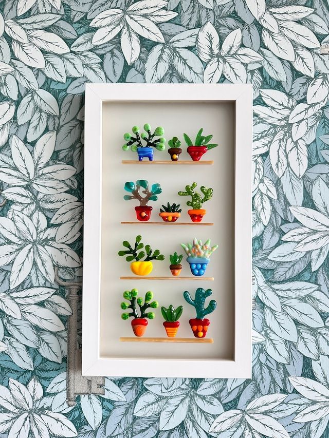 a white frame with some plants in it on top of a blue and green wall