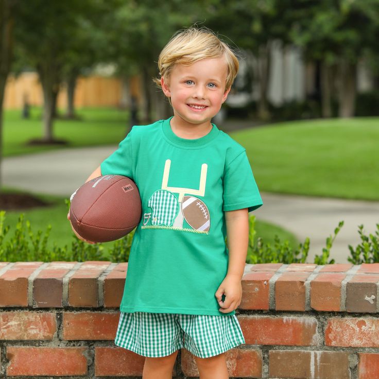 Get ready to score big with Our Touch Down Tee! This Kelly Green shirt features a playful applique design of a football, helmet, and goalpost. Your little one will be the star of the game. Match it with our Gingham Shorts in Green. Multiple color options & sibling matches available!  Size Chart Measurement in inches Shirt 6M 9M 12M 18M 24M 2 3 4 5 6 7 8 10 12 Length 12 12.75 13.5 14.25 15  16    16.75 17.5 18.25 19  19.75 20.5 21.75 23 Chest 10.25 10.5 11    11.25 11.75 12.25 12.5 13    13.25 13.75 14 14.5 15.25 16   Measurements may vary an up to an inch due to fabric variations. Measurements are meant to be used as a guide. 95% Cotton 5% Spandex. Fits true to size. Touch Down Tee- Kelly Green Green Tops For College Football Season, Green College Football Season Tops, Green Tops For Football Season Sports Events, Green Tops For Football Season Fan Gear, Green Tops For Football Season Sports Fans, Green T-shirt For Game Day With School Spirit, Green School Spirit T-shirt For Game Day, Green Game Day T-shirt With School Spirit, Sports Fan Tops With Mascot For Football Season