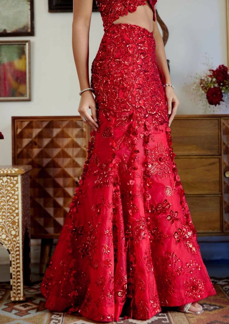 This structured red mermaid lehenga set personifies the emblem of romantic glamour. The set features intricate embroidery of cutdana work and dori with red sequins, beads, and floral applique work adorning both the skirt and blouse. Its focal point is the tassel detailing flowing at the bottom of the skirt with cute flower motifs made of sequins. Sleeveless blouse with floral applique detailing highlighted with nalki crystals and beads. Blouse contains a metal hook on the front side. Heavily embroidered dupatta with botanical motifs detailing accentuated with sparkling sequins and crystals. Lehenga skirt adorned with floral applique handwork detailing and drop-down tassels adorning the bottom of the skirt. Lehenga contains a left zipper for support along with a metal hook. Red Mermaid, Lehenga Skirt, Red Sequin, Nehru Jackets, Skirt And Blouse, Western Wedding, Floral Applique, Wedding Service, Short Suit