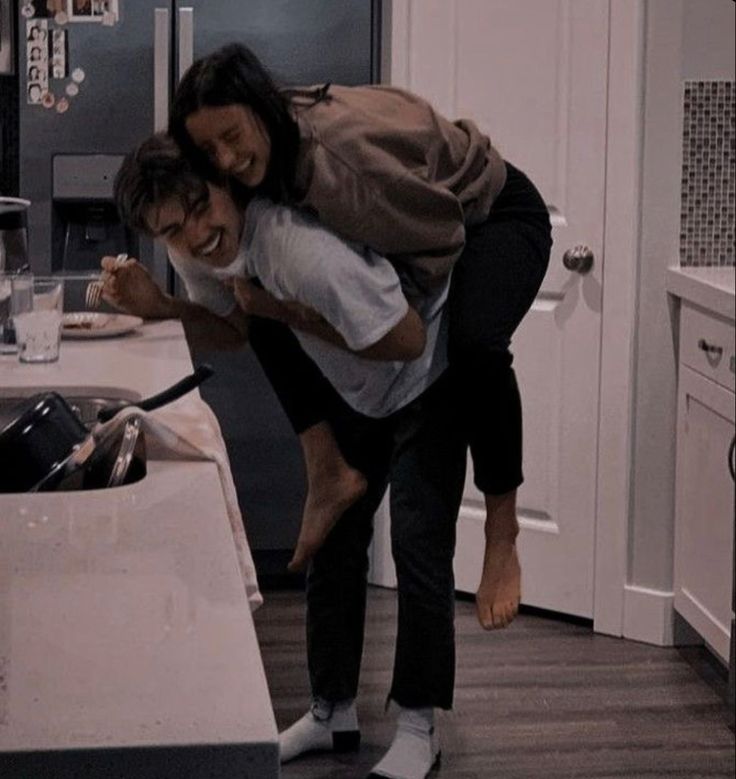 two people are in the kitchen and one is holding onto another person's head