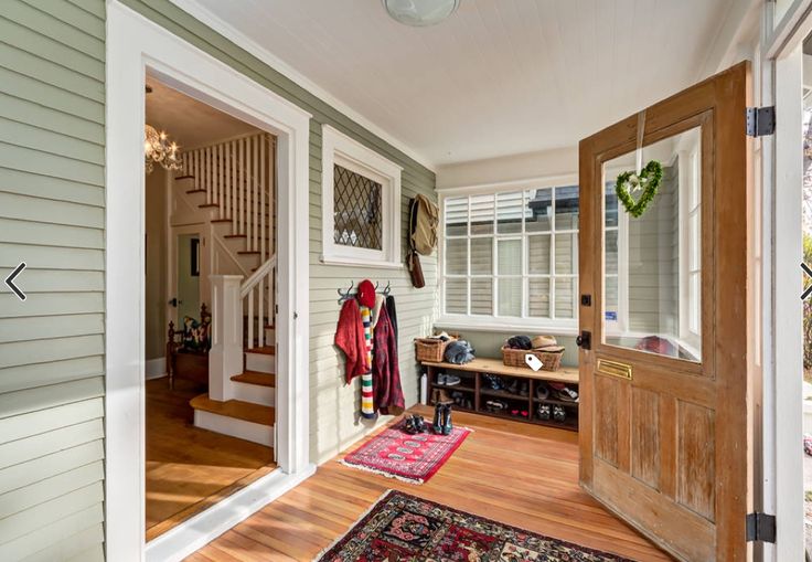 the entry way to a home with wood floors and white walls, has a wooden door that leads into another room