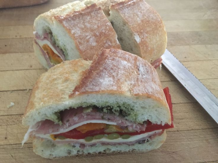 a cut in half sandwich sitting on top of a cutting board next to a knife