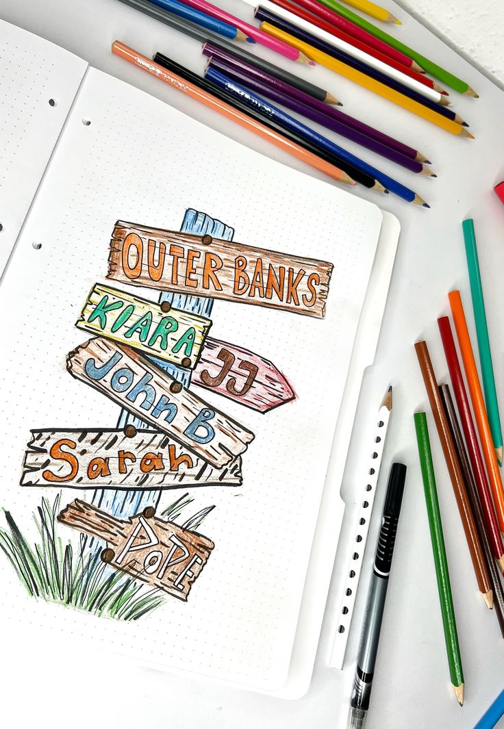 an open notebook with colorful markers and pencils next to it