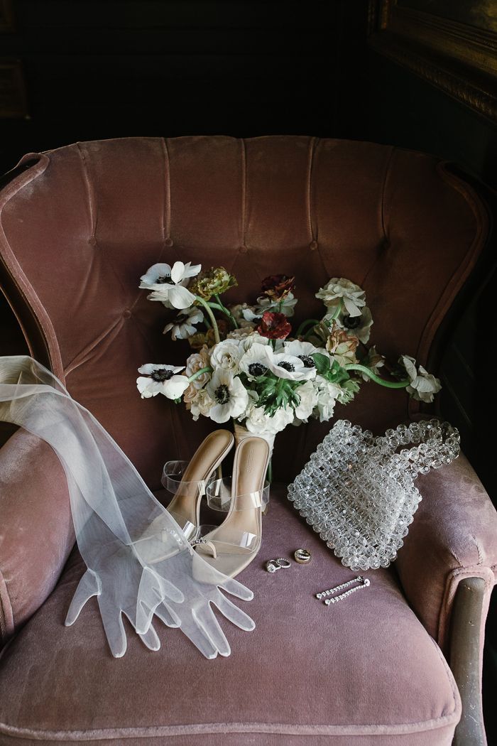 a bouquet of flowers sitting on top of a chair next to a pair of gloves