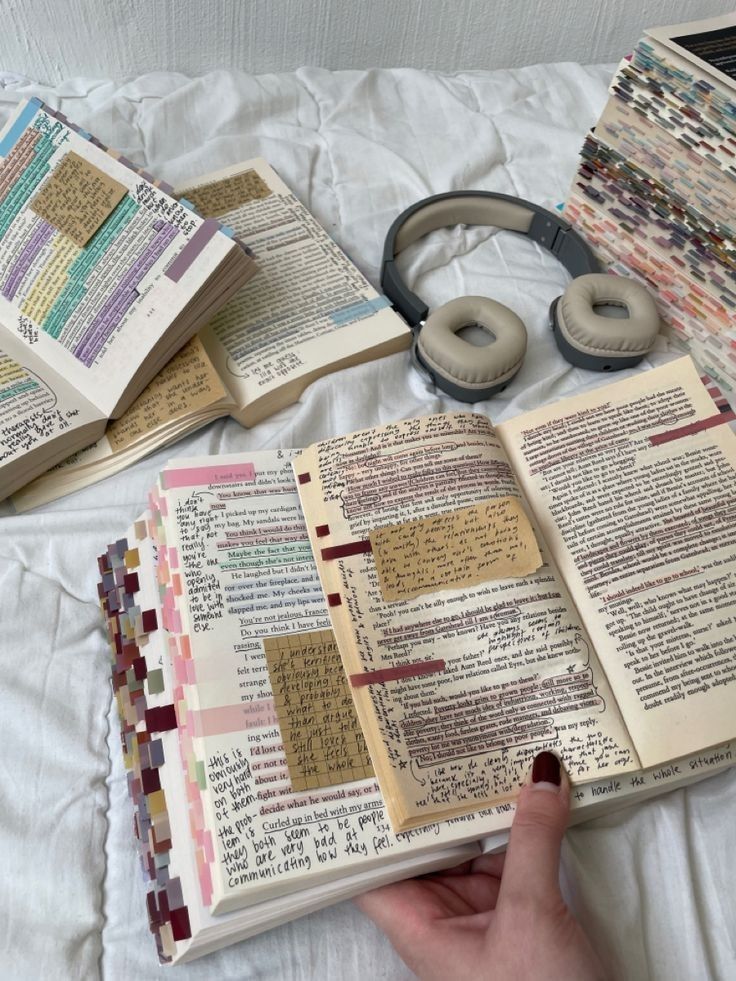 an open book sitting on top of a bed next to headphones