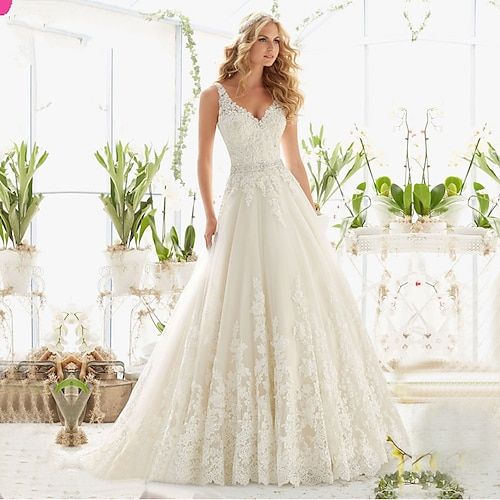 a woman in a wedding dress standing next to plants